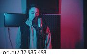 A man in headphones rapping in the studio gesticulates while recording his track. Стоковое видео, видеограф Константин Шишкин / Фотобанк Лори