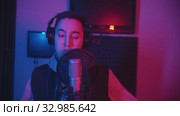 A man in hoodie rapping through the pop-filter in the microphone - recording his track. Стоковое видео, видеограф Константин Шишкин / Фотобанк Лори