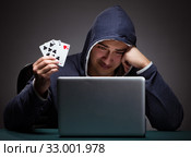 Young man wearing a hoodie sitting in front of a laptop computer. Стоковое фото, фотограф Elnur / Фотобанк Лори