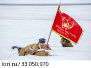 Russia, Samara, February 2017: Red banner "Proletarians of all countries unite" in the hands of a fighter. Historical reconstruction. The text in Russian: Workers of all countries unite. Редакционное фото, фотограф Акиньшин Владимир / Фотобанк Лори