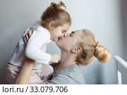 Счастливая мама держит на руках и целуе свою дочь / Happy mom hugs and kisses laughing daughter, holding her in her arms. family, motherhood concept. Стоковое фото, фотограф Сергей Тиняков / Фотобанк Лори