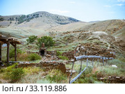 Old ruined log house and stone stove in the yard in Crimean steppe on a background of mountains (2016 год). Стоковое фото, фотограф katalinks / Фотобанк Лори