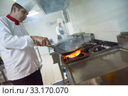 chef in hotel kitchen prepare food with fire. Стоковое фото, фотограф Benis Arapovic / PantherMedia / Фотобанк Лори