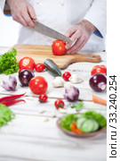 Chef cutting a red tomato his kitchen. Стоковое фото, фотограф Volodymyr Melnyk / PantherMedia / Фотобанк Лори