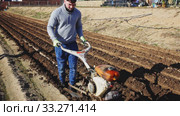 Experienced farmer plowing field with hand tractor, preparing soil for seeding. Spring agricultural works. Стоковое видео, видеограф Яков Филимонов / Фотобанк Лори