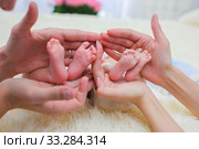 Mom and dad hands hold small legs of their two newborn twin babies. Стоковое фото, фотограф Екатерина Кузнецова / Фотобанк Лори