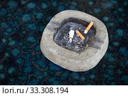 Ashtray with three cigarette butts stands on a blue table. Стоковое фото, фотограф Олег Белов / Фотобанк Лори