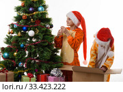 Девочки наряжают новогоднюю елку, одна из них копается в коробке с игрушками. Стоковое фото, фотограф Иванов Алексей / Фотобанк Лори