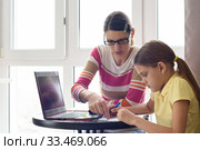 Репетитор на дому учит ребенка, сидя за столом и с использования компьютера. Стоковое фото, фотограф Иванов Алексей / Фотобанк Лори