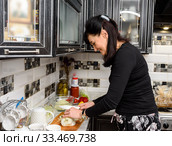 Немолодая женщина готовит еду на кухне (2020 год). Редакционное фото, фотограф Игорь Низов / Фотобанк Лори