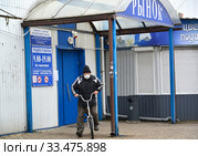 Пожилой мужчина в медицинской маске отъезжает на велосипеде от дверей рынка. Эпидемия коронавируса COVID-19 в России. Калининград (2020 год). Редакционное фото, фотограф Ирина Борсученко / Фотобанк Лори