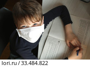 Child with antiviral mask doing his homework in quarantine. Стоковое фото, фотограф Попова Ольга / Фотобанк Лори