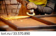 Grinding the seams of an iron frame - bright sparkles comes off the metal. Стоковое фото, фотограф Константин Шишкин / Фотобанк Лори