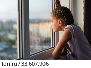Скучающая дома на карантине девочка смотрит в окно. Стоковое фото, фотограф Иванов Алексей / Фотобанк Лори