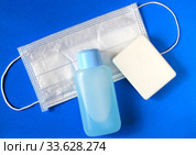 Flat lay of soap, medical surgical mask and hand sanitize on blue background. Стоковое фото, фотограф Попова Ольга / Фотобанк Лори