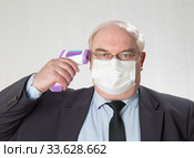 Close up portrait of handsome man in a protective medical mask  and glasses with IR thermometer. Стоковое фото, фотограф Михаил Котов / Фотобанк Лори