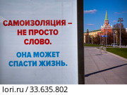 Баннер на центральной улице города Москвы на фоне Московского кремля, призывающий остаться дома, во время эпидемии коронавируса COVID-19 в России (2020 год). Редакционное фото, фотограф Николай Винокуров / Фотобанк Лори