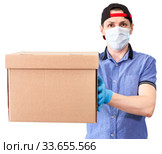 Courier stretching out cardboard box, delivery service, man with surgical mask and blue neoprene gloves, isolated on white background. Стоковое фото, фотограф Кекяляйнен Андрей / Фотобанк Лори