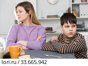 Upset mother and unhappy son sitting after quarrel indoors. Стоковое фото, фотограф Яков Филимонов / Фотобанк Лори