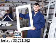 Production workers in coverall with different finished PVC profiles and windows at factory. Стоковое фото, фотограф Яков Филимонов / Фотобанк Лори