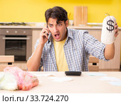 Young man calculating expences for vegetables in kitchen. Стоковое фото, фотограф Elnur / Фотобанк Лори