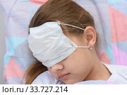 Девочка заснула в кровати, на лице и глаза натянула медицинскую маску, крупный план. Стоковое фото, фотограф Иванов Алексей / Фотобанк Лори