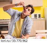 Young man calculating expences for vegetables in kitchen. Стоковое фото, фотограф Elnur / Фотобанк Лори