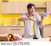 Young man calculating expences for vegetables in kitchen. Стоковое фото, фотограф Elnur / Фотобанк Лори
