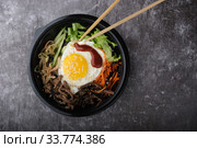Korean dish bibimbap. Top view close up. Nearby are the Korean sticks. Стоковое фото, фотограф Evgeny Miller / Фотобанк Лори