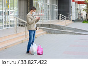 Мужчина в медицинской маске и с покупками остановился на пустой улице что бы ответить на звонок. Стоковое фото, фотограф Иванов Алексей / Фотобанк Лори