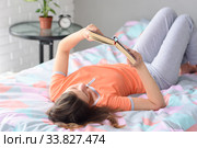 Девушка в выходной день лежит дома в кровати на спине и читает книгу. Стоковое фото, фотограф Иванов Алексей / Фотобанк Лори