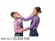 Старшая девочка таскает за ухо младшую, изолировано. Стоковое фото, фотограф Иванов Алексей / Фотобанк Лори