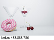 A flower in a glass close-up for a screensaver. In the background is a donut glass. And next to it is sweet cherry. Стоковое фото, фотограф Evgeny Miller / Фотобанк Лори