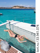 Woman relaxing on a summer sailing cruise,lying in hammock of luxury catamaran near picture perfect white sandy beach on Spargi island in Maddalena Archipelago, Sardinia, Italy. Стоковое фото, фотограф Matej Kastelic / Фотобанк Лори