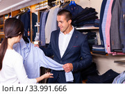 Seller helps buyer to choose a shirt in the store. Стоковое фото, фотограф Яков Филимонов / Фотобанк Лори