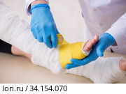 Young leg injured woman visiting old doctor traumatologist. Стоковое фото, фотограф Elnur / Фотобанк Лори