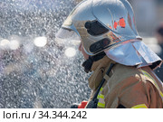 Side view of rescuer in silver mirrored helmet and protective uniform, water drops falling on firefighter Emercom of Russian Federation MChS (2019 год). Редакционное фото, фотограф А. А. Пирагис / Фотобанк Лори