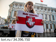 Девушка держит плакат с надписью на белорусском "Жыве Беларусь!" на фоне здания посольства Республики Беларусь в Москве, Россия (2020 год). Редакционное фото, фотограф Николай Винокуров / Фотобанк Лори