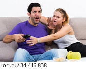 Couple on sofa quarreling because of TV remote. Стоковое фото, фотограф Яков Филимонов / Фотобанк Лори