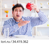 Man running out of money in restaurant and using savings from pi. Стоковое фото, фотограф Elnur / Фотобанк Лори