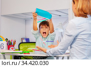 Autistic boy throws pens during development lesson. Стоковое фото, фотограф Сергей Новиков / Фотобанк Лори