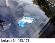 Синие перчатки и одноразовые медицинские маски лежат в салоне автомобиля у места водителя в период пандемии коронавируса Ковид-19 (COVID-19) Стоковое фото, фотограф Grigory_Gez / Фотобанк Лори