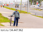 Russia Samara June 2020: A young man stands with a bicycle on the path in the city on the street on a summer day. Редакционное фото, фотограф Акиньшин Владимир / Фотобанк Лори