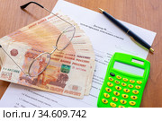 На столе лежит договор купли продажи земельного участка, пачка денег, калькулятор, ручка и очки. Стоковое фото, фотограф Иванов Алексей / Фотобанк Лори