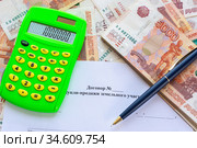 На договоре купли продажи земельного участка лежат калькулятор с числом 1000000, пачка денег и ручка. Стоковое фото, фотограф Иванов Алексей / Фотобанк Лори
