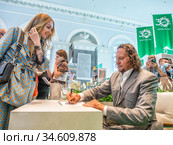Сергей Полонский подписывает читательнице свою книгу "Взламывая стереотипы. Освобожденный" на Московской Международной Книжной ярмарке (2020 год). Редакционное фото, фотограф Сайганов Александр / Фотобанк Лори