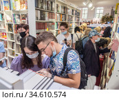 Посетители Московской международной книжной ярмарки среди стеллажей с книгами (2020 год). Редакционное фото, фотограф Сайганов Александр / Фотобанк Лори
