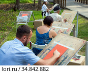 Взрослые люди рисуют мелками на бумаге в городском парке, город Воронеж (2019 год). Редакционное фото, фотограф Вячеслав Палес / Фотобанк Лори
