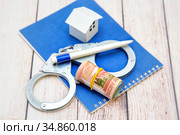 Деньги, ручка, наручники и домик на блокноте. Планирование махинаций на рынке недвижимости. Стоковое фото, фотограф Наталья Осипова / Фотобанк Лори