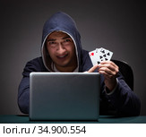 Young man wearing a hoodie sitting in front of a laptop computer. Стоковое фото, фотограф Elnur / Фотобанк Лори